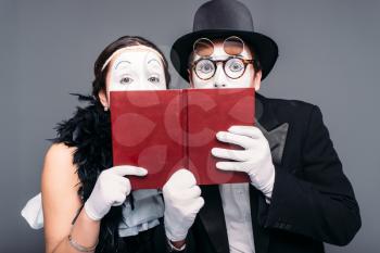 Two comedy performers posing with book. Pantomime theater actor and actress performing