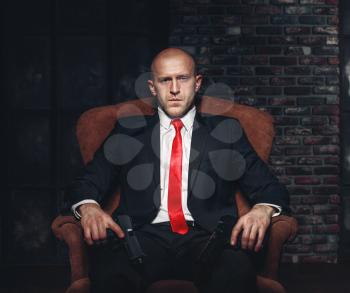 Contract assassin wallpaper, background or poster concept. Bald killer in suit and red tie sitting in a chair and holding pistols in hands