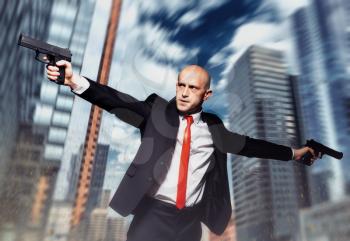 Serious contract killer shooting action wallpaper, background or poster. Bald assassin in red tie fires a pistols with two hands on city street.  
Professional special agent on secret mission