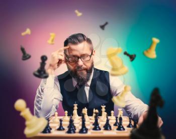 Pensive male chess player in glasses calculate movies and game strategy against chessboard. Figures flying around chessplayer.