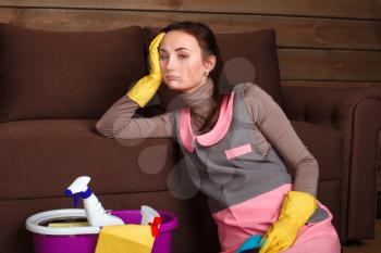 Tired female cleaning servisce worker in uniform and rubber gloves asleep on a couch. Housekeeping concept