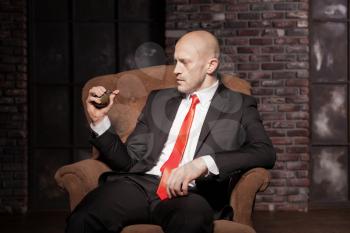 Bald killer in suit and red tie ready to pull a grenade pin