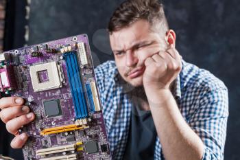 Service engineer fixing problem with computer motherboard. Repairman makes electronic components diagnostic