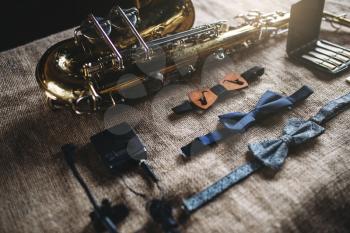Saxophone, brass band instrument equipment on grunge sack background, closeup view. Classical sax, mouthpieces, bowtie and microphone on canvas texture. Jazz music
