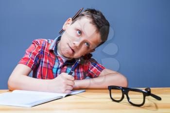 Young pupil at the desk doing homework. Little kid writing in notebook 