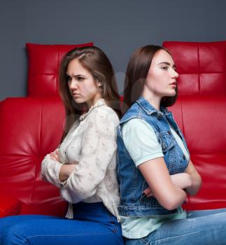 Women quarrel,two quarreling girlfriends sits on red leather couch
