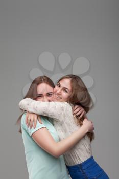 Two happy girlfriends hugs together, studio photo shoot. Female friendship