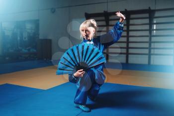 Female wushu master with fan, martial arts. Woman in blue cloth on fight training