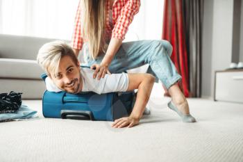 Cheerful girl Packed her husband in a suitcase. Fees on vacation concept