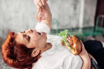 Overweight woman eats sandwich, bulimic, obesity problem. Unhealthy lifestyle, fatty female