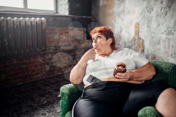 Fat woman sits in a chair and eats sweets, overweight. Unhealthy lifestyle, obesity
