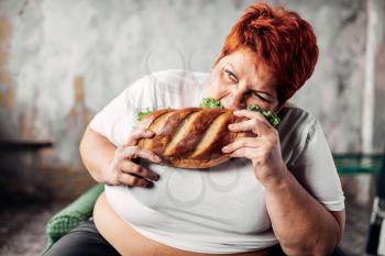 Fat woman eats sandwich, overweight and bulimic. Unhealthy lifestyle. Obesity