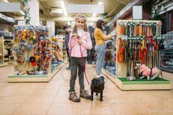 Little girl with puppy in pet shop, friendship. Kid with dog chooses accessories in petshop, caring for domestic animals