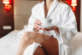 Female person in bathrobe holds in hand a cup of coffee, good morning concept. Healthy lifestyle, light vitamin breakfast