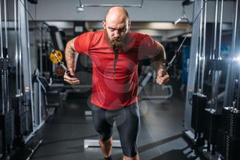 Strong athlete in sportswear, training on exercise machine in gym. Bearded man on workout in sport club, healthy lifestyle