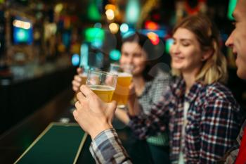 Football fans drinks light beer at the counter in sports bar. Tv broadcasting, young friends celebrates win of the favorite team, success game celebration in pub