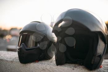 Two biker helmets with sunglasses and visor on concrete parapet closeup view, nobody, biking concept