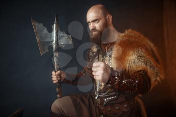 Viking with axe, martial spirit, barbarian image, side view. Ancient warrior in smoke