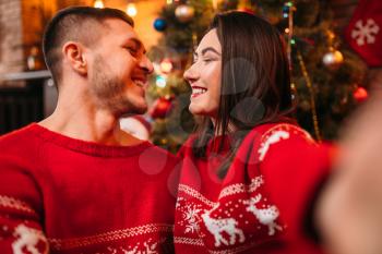Love couple makes selfie, romantic Christmas celebration. Xmas holidays, happy relationship of man and woman, festive decoration on background