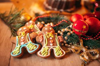 Xmas gingerbread man, holiday dessert closeup. Christmas traditional symbol, festive sweet food, fir tree branch, red balls