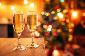 Two glasses with champagne,nobody, christmas decoration on background, blur effect. Xmas symbol to drink sparkling wine