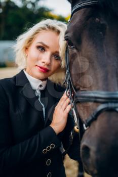 Portrait of blonde woman with horse, horseback riding. Brown stallion, leisure with animal, equestrian sport