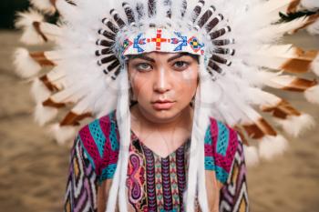 Face of young American Indian woman, Cherokee, Navajo. Headdress made of feathers of wild birds