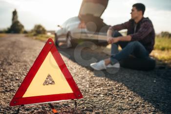 Broken car concept, breakdown triangle on asphalt road. Problem with vehicle, warning sign