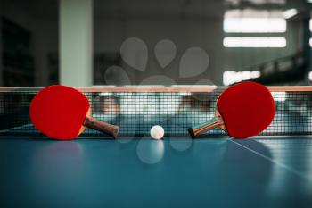 Two tennis rackets and ball against net on the table, game concept. Ping pong sport equipment