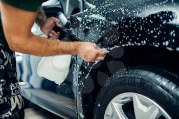 Worker disperses soapy water, preparing car for protect against chips and scratches. Paint protection. Protective coating