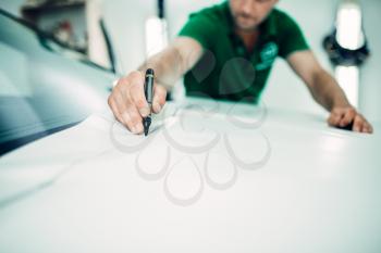 Professional automobile paint protection film installation process. Worker hands prepares protect coating against chips and scratches