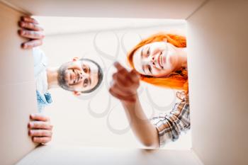Happy man and woman, view from inside the cardboard box, moving to new house. Young couple, housewarming