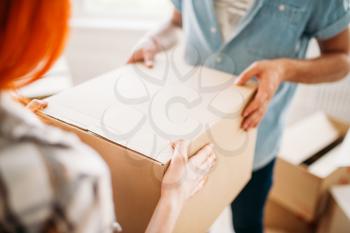 Male and female person hands holds carton box, housewarming. Moving to new house