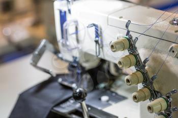 Sewing or overlock machine closeup, nobody, cloth industry. Factory production, sew manufacturing