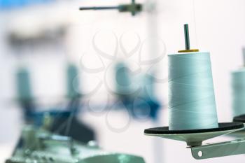 Spool of white threads on sewing machine, closeup. Cloth factory, weaving, textile production, clothing industry