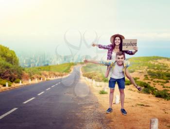 Hitchhiking couple holds blank cardboard, happy hitchhikers travels anywhere. Hitchhike adventure of young man and woman
