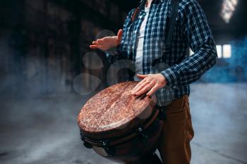 Male drummer playing on wooden drum, musician in motion. Bongo, musical percussion instrument, ethnic music