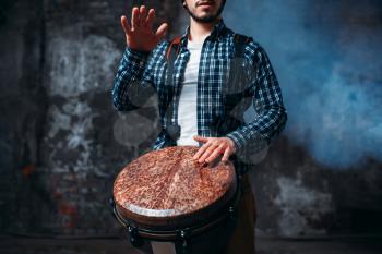 Male drummer playing on wooden drum, musician in motion. Bongo, musical percussion instrument, ethnic music