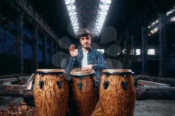 Drummer plays on african wooden drums in factory shop, beat rhythm, musician in motion. Djembe, musical percussion instrument