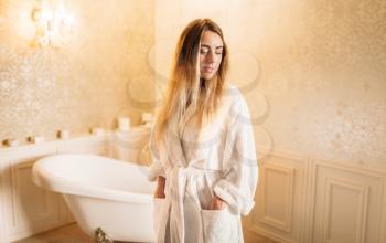 Young woman in white bathrobe, bathroom on background. Bodycare and hygiene, healthcare 