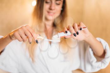 Young woman with toothbrush and toothpaste in hand. Morning mouth hygiene, tooth cleaning