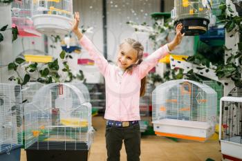 Happy little girl between cages for domestic birds in pet shop. Petshop advertising concept