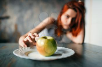 Female hand reaches plate with apple. Weight loss concept, fat burning, hard dieting