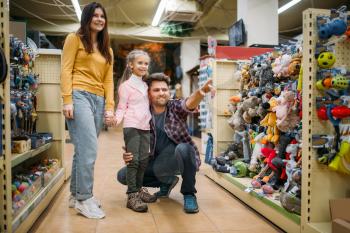Family in pet shop, happy customers. Father, mother and little daughter chooses domestic animal in petshop