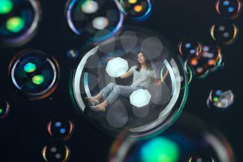 Cute woman flying in big soap bubble, happy fantasy. Female person blowing colorful balloons