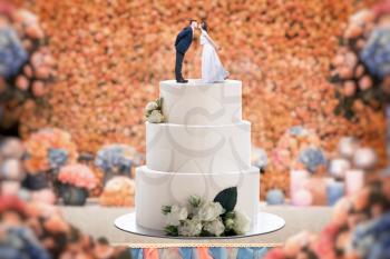 Wedding cake with bride and groom on the top. Pie for newlyweds with little figurines, love symbol