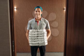 Pizza delivery man with boxes, delivering service. Courier from pizzeria holds cardboard package indoors