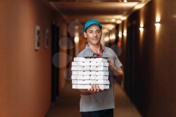 Delivery man with fresh pizza in carton boxes, delivering service. Courier from pizzeria holds cardboard packages indoors