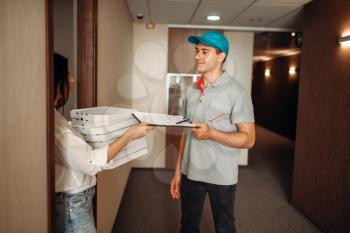 Female customer takes order blank on pizza from delivery man, fast delivering service. Courier from pizzeria and woman with carton boxes at the door
