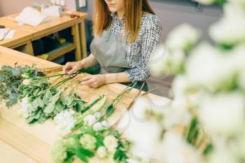 Female florist with plant bunches in hands makes flower bouquet. Floral business, decoration tools